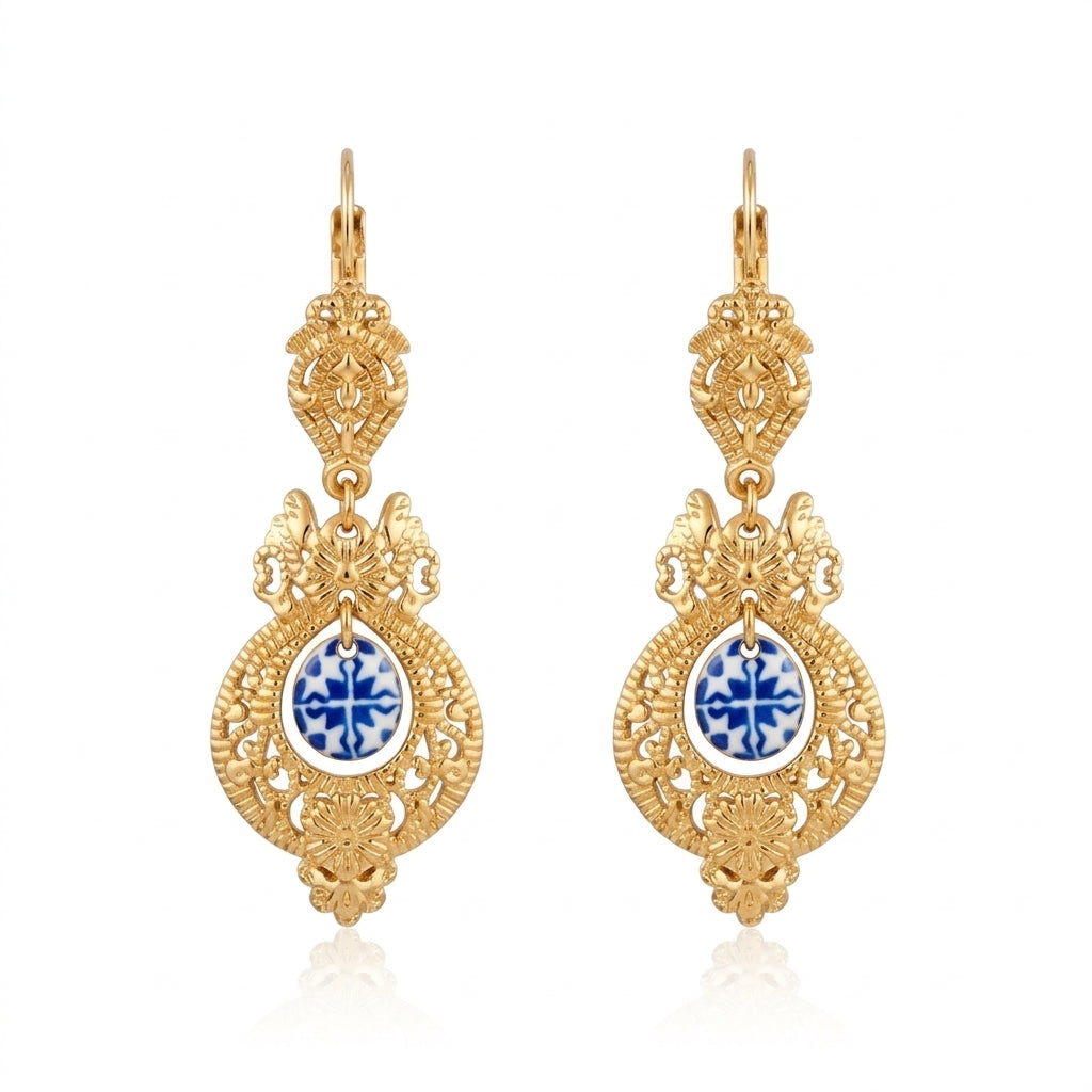 Boucles d'oreilles pendantes dorées de style baroque ornées d'un médaillon en céramique bleue et blanche de type azulejo.